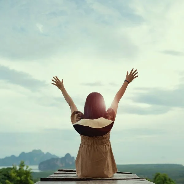 Salud integral con mujer levantando los brazos al cielo